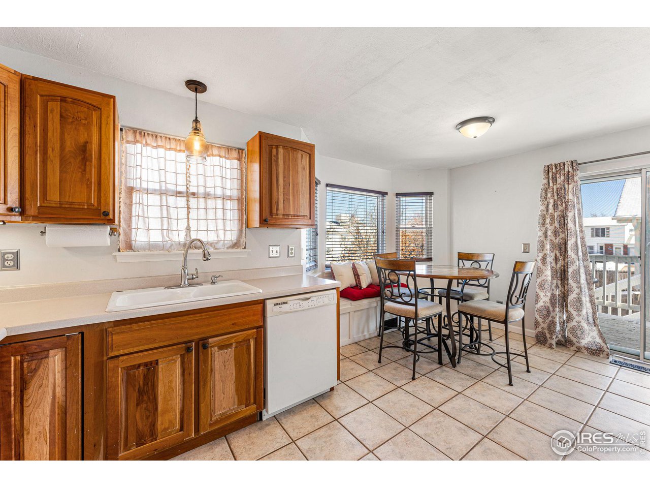 Kitchen and dining area with wood cabinets, tiled floor, and a round table beside a sliding glass door.