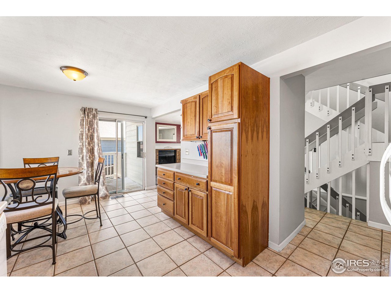 Kitchen and dining area with tall wood cabinets, tiled floors, and a staircase.