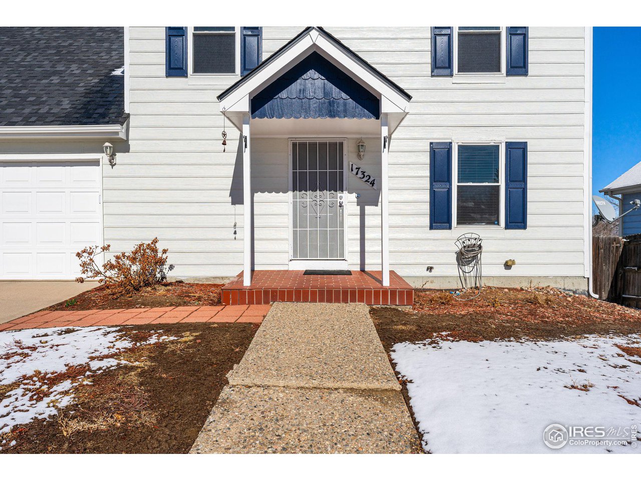 White two-story home with blue shutters, a covered front entry, and a snowy yard.