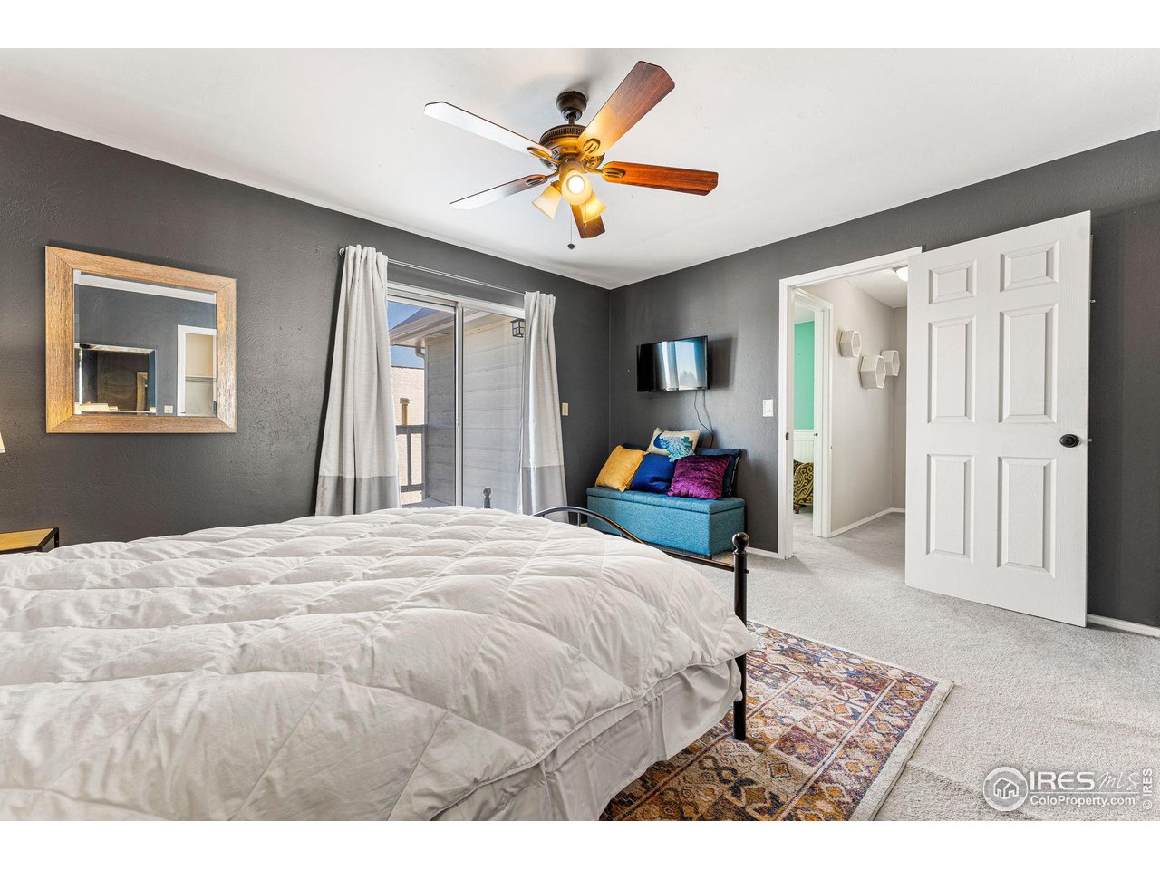 Bedroom with dark gray walls, a large bed, sliding glass doors, and a blue loveseat.
