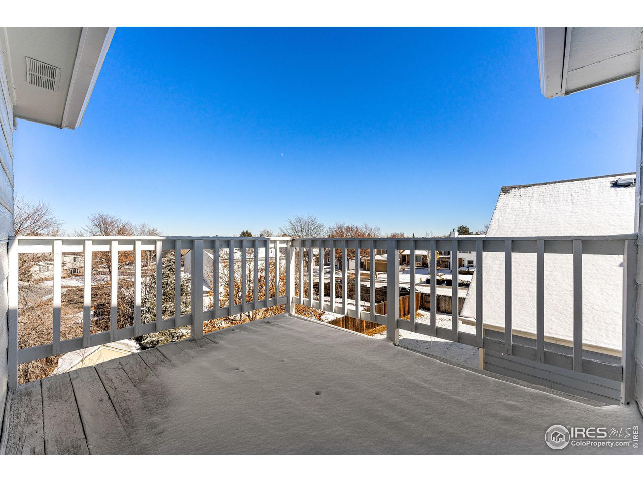 Covered balcony overlooking snow-dusted homes and leafless trees.