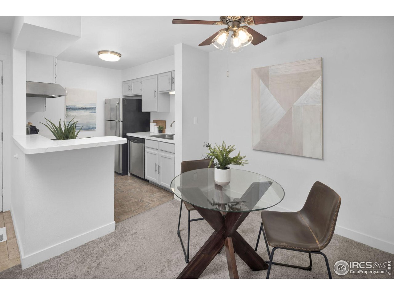 Open kitchen and dining area with white cabinets, stainless appliances, and a round glass table.