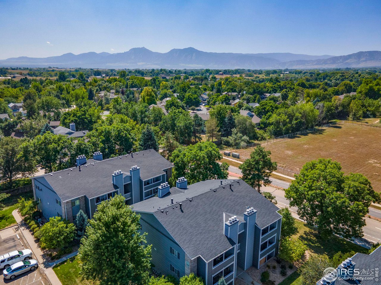 Aerial view of Boulder homes and apartment buildings with the Rocky Mountains in the distance.
