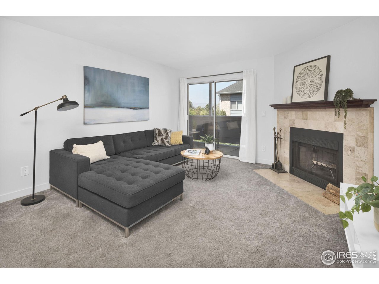 Living room with a gray sectional, tiled fireplace, and sliding glass door to a balcony.