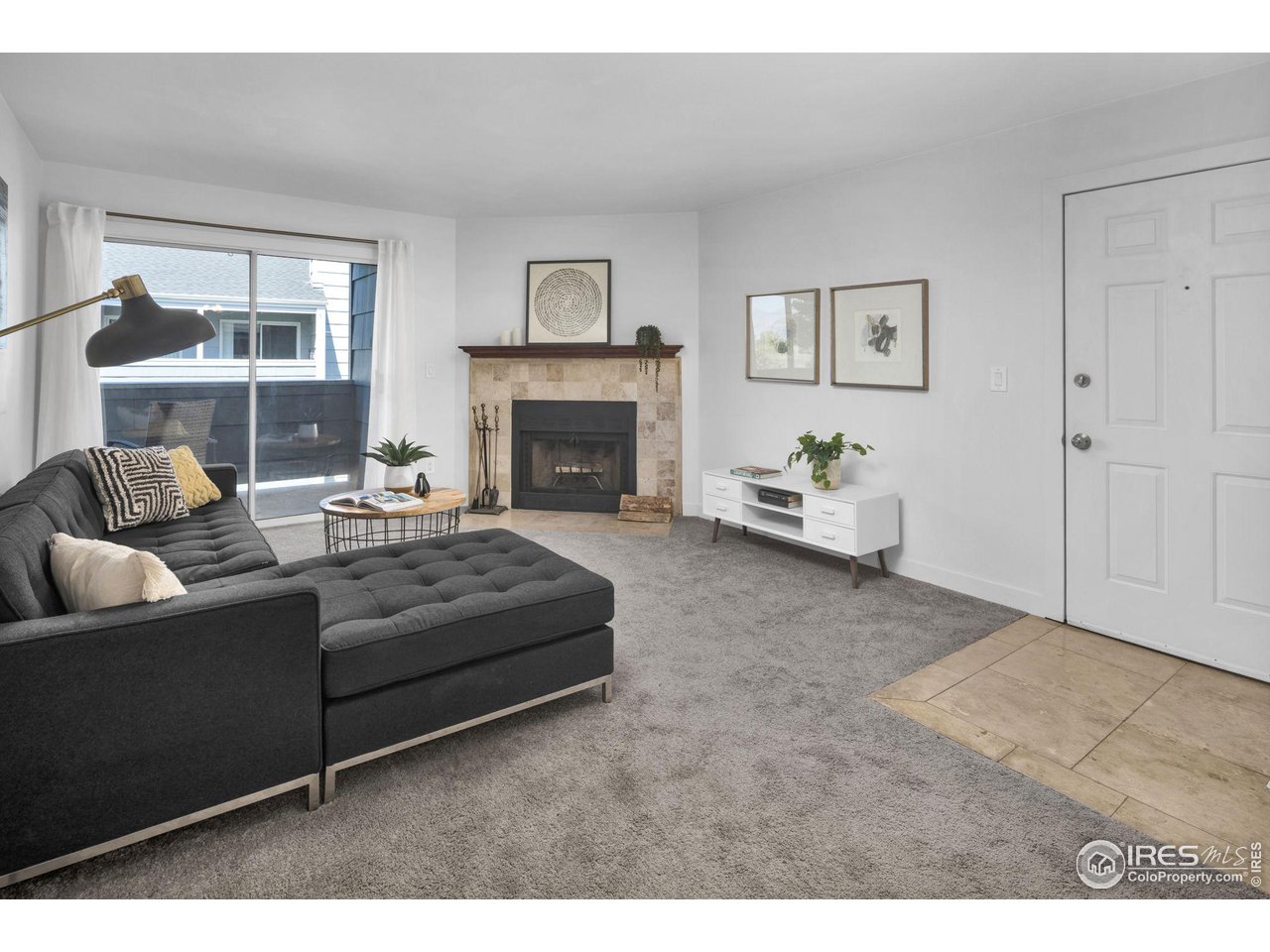 Living room with a dark sectional, tiled fireplace, and sliding glass door to a patio.