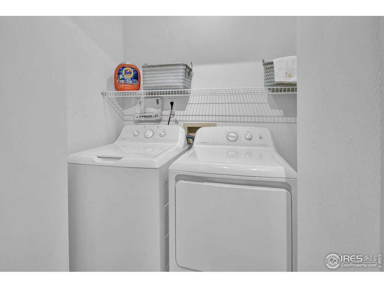 Laundry room with a top-loading washer, front-loading dryer, and wire storage shelf.