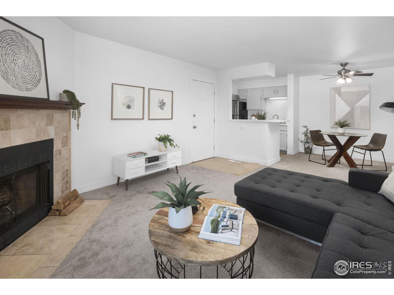 Living room with a stone fireplace, gray sectional sofa, and adjoining dining area.