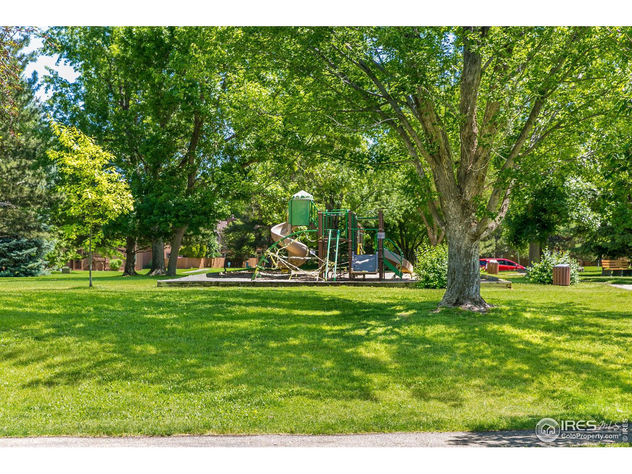Neighborhood park with a shaded playground and broad grassy lawn.