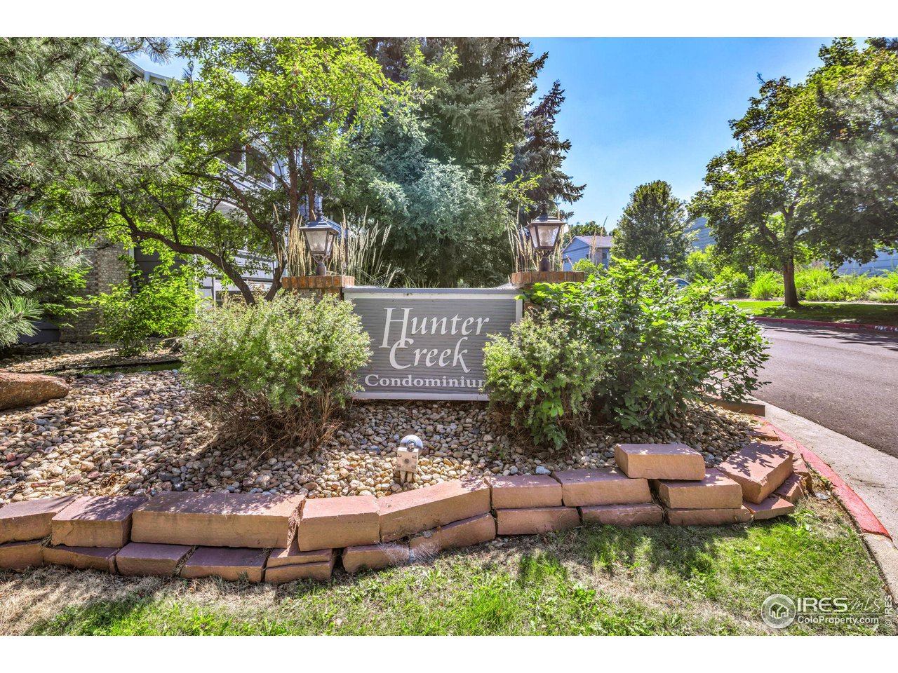 Hunter Creek Condominiums entrance sign amid trees and landscaped rock beds.