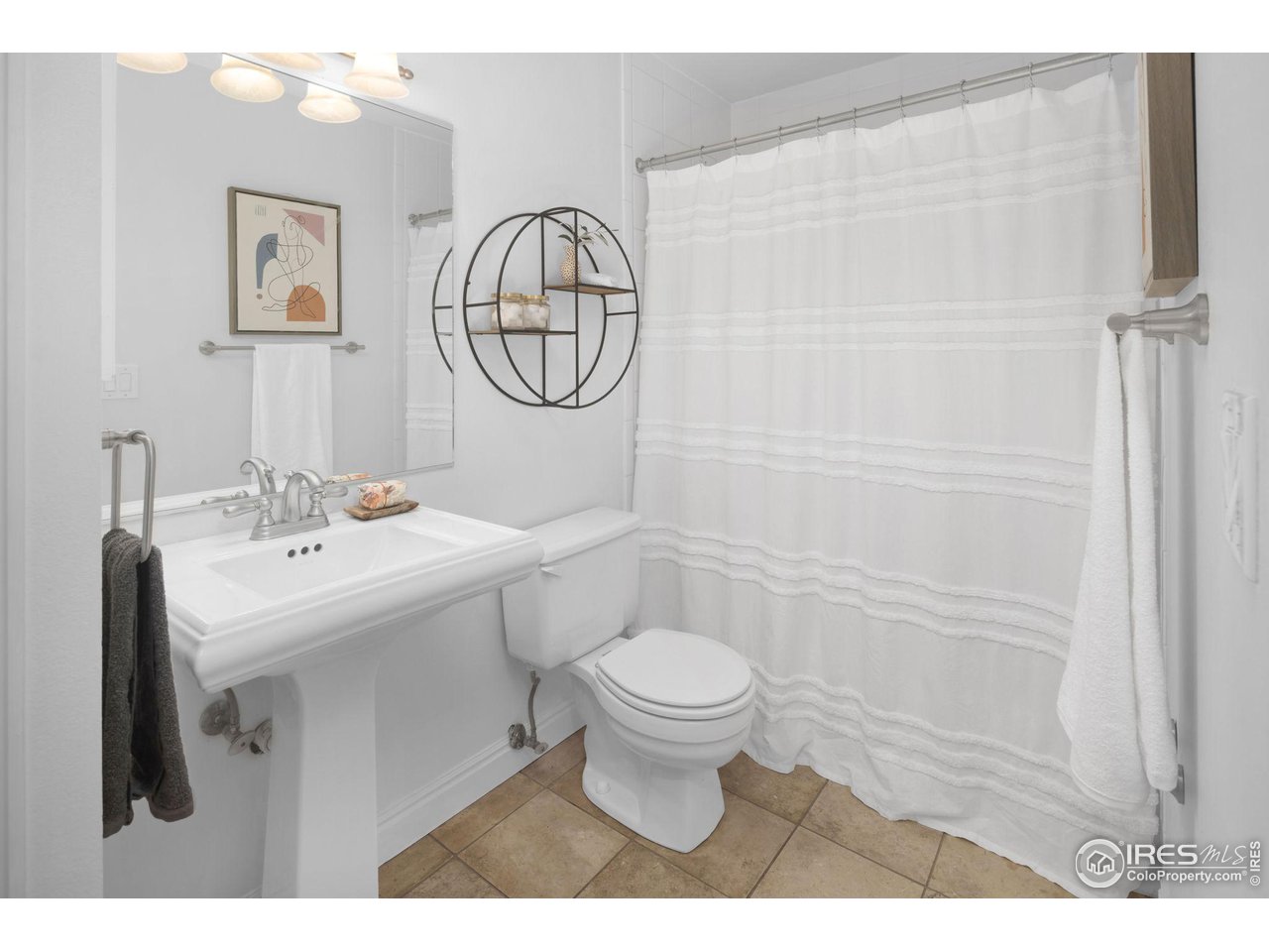Bathroom with a pedestal sink, white shower curtain, and tan tile floor.
