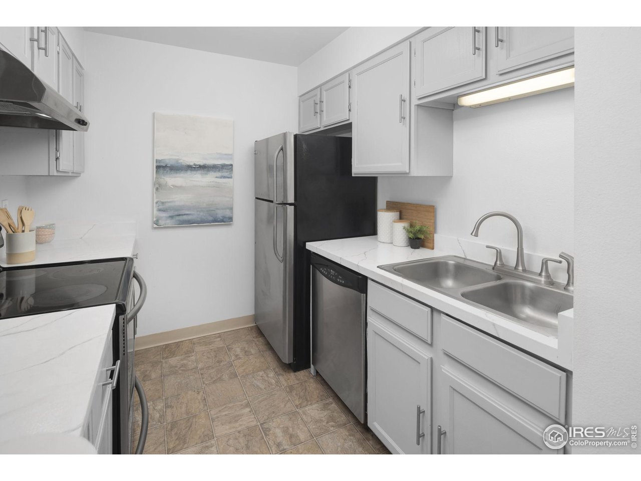 Bright kitchen with white cabinets, stainless steel appliances, and a double-basin sink.