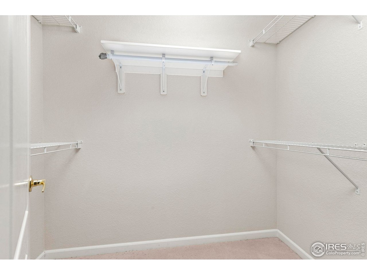 Empty walk-in closet with white wire shelving along three walls.