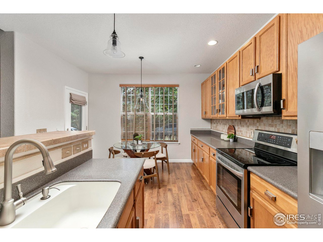 Kitchen with warm wood cabinets, stainless steel appliances, and a dining table beside a window.