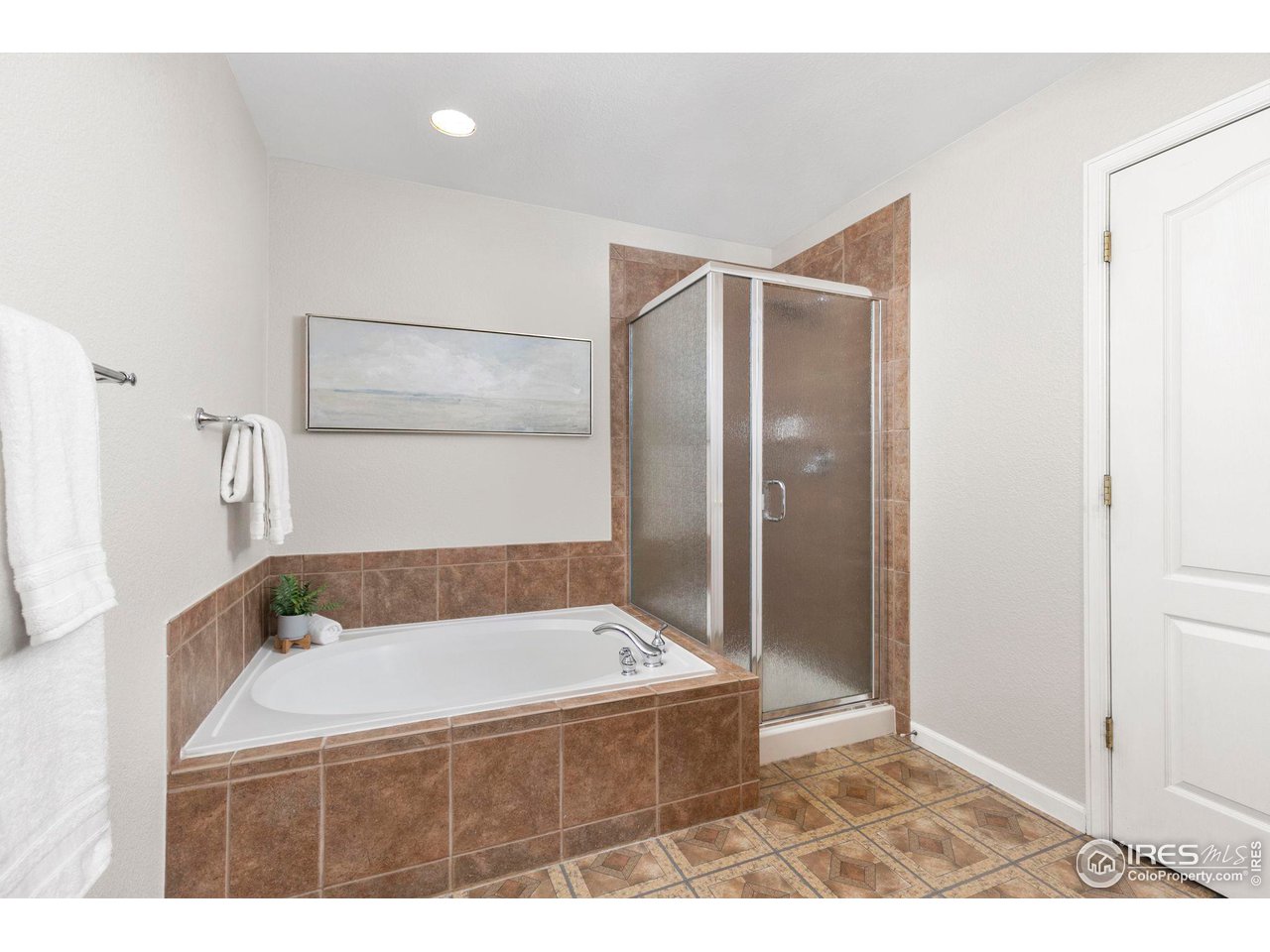 Bathroom with a built-in soaking tub, frosted-glass shower, and brown tile.
