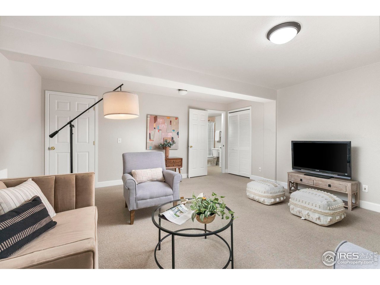 Furnished living room with a beige sofa, gray armchair, and television.