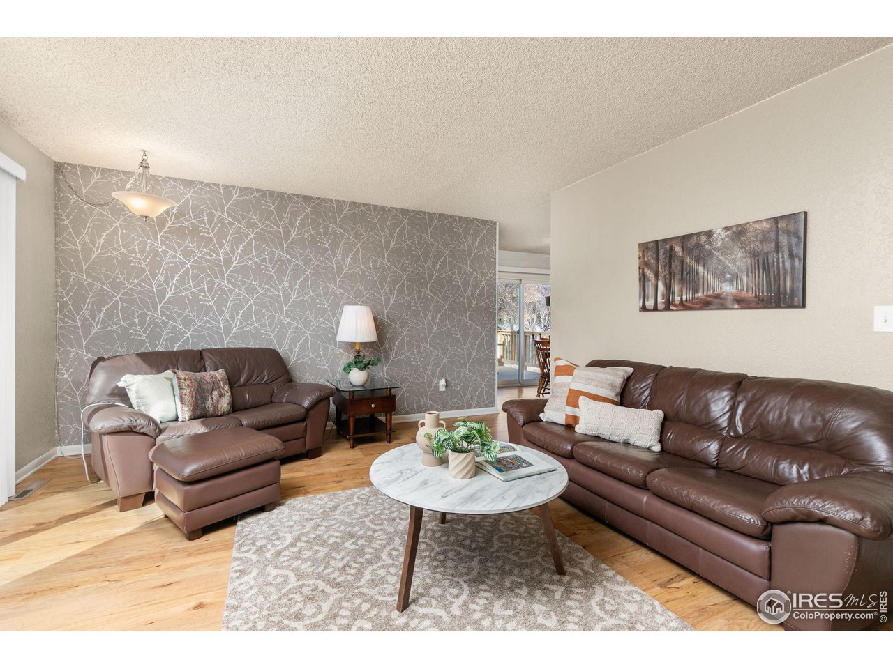 Living room with brown leather sofas, a round coffee table, and a gray branch-pattern accent wall.