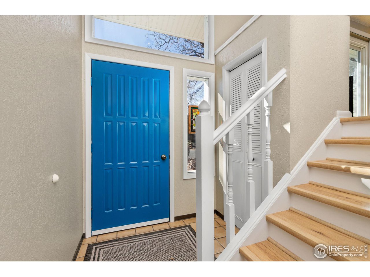 Entryway with a bright blue front door and a staircase with light wood treads.