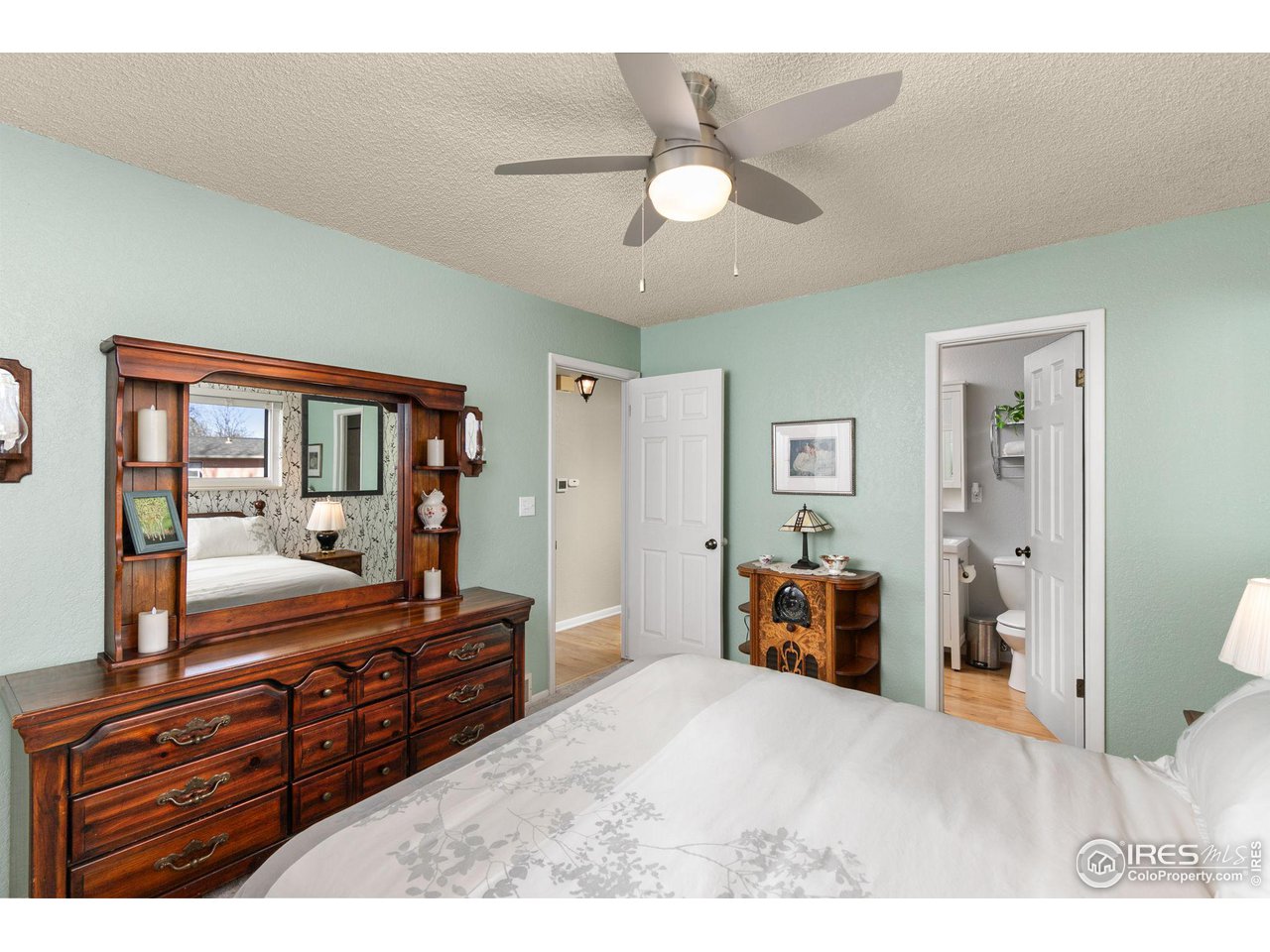 Bedroom with pale green walls, a large dark wood dresser, and a ceiling fan.