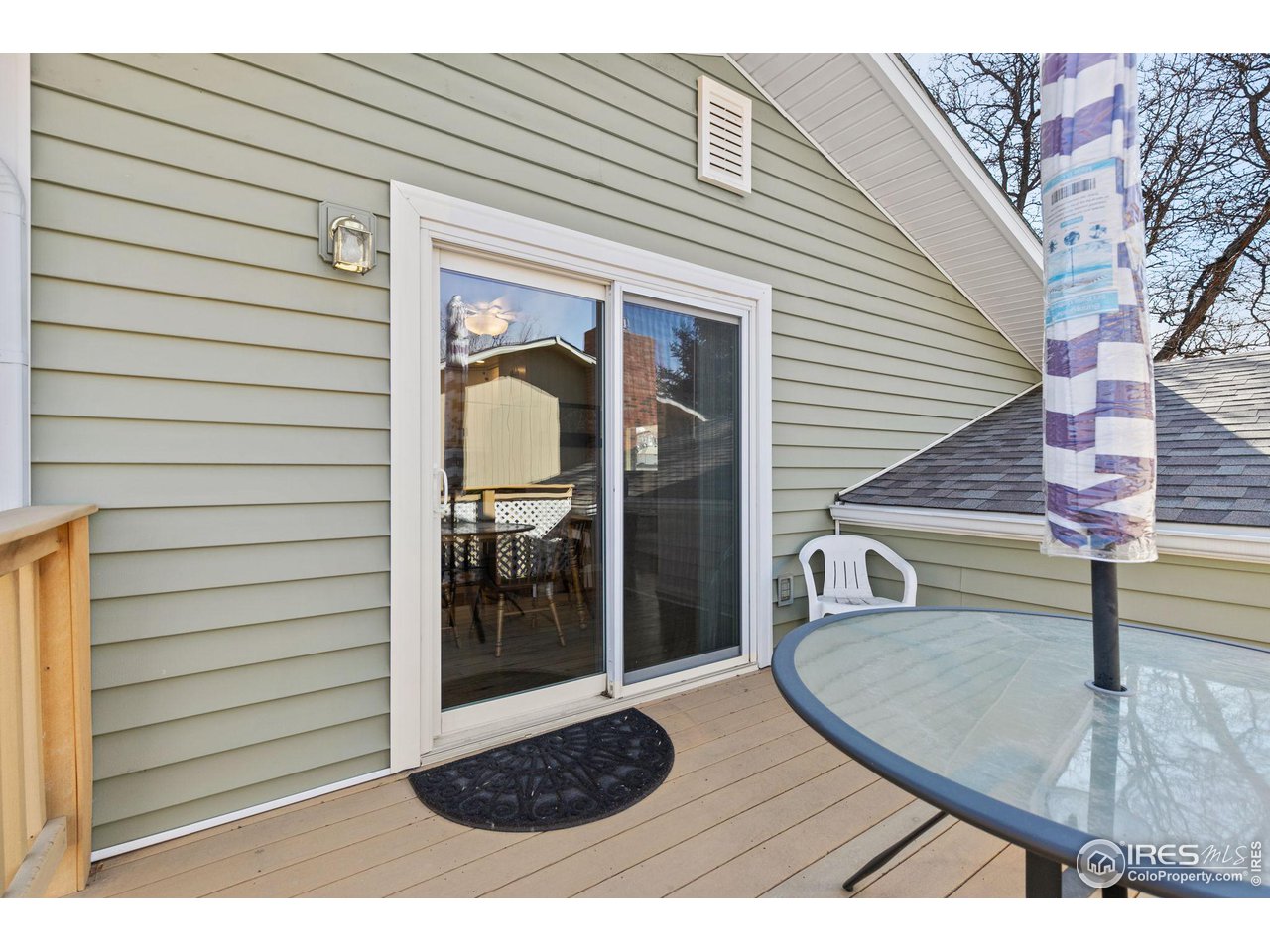 Raised wooden deck with a glass patio table and sliding glass door.