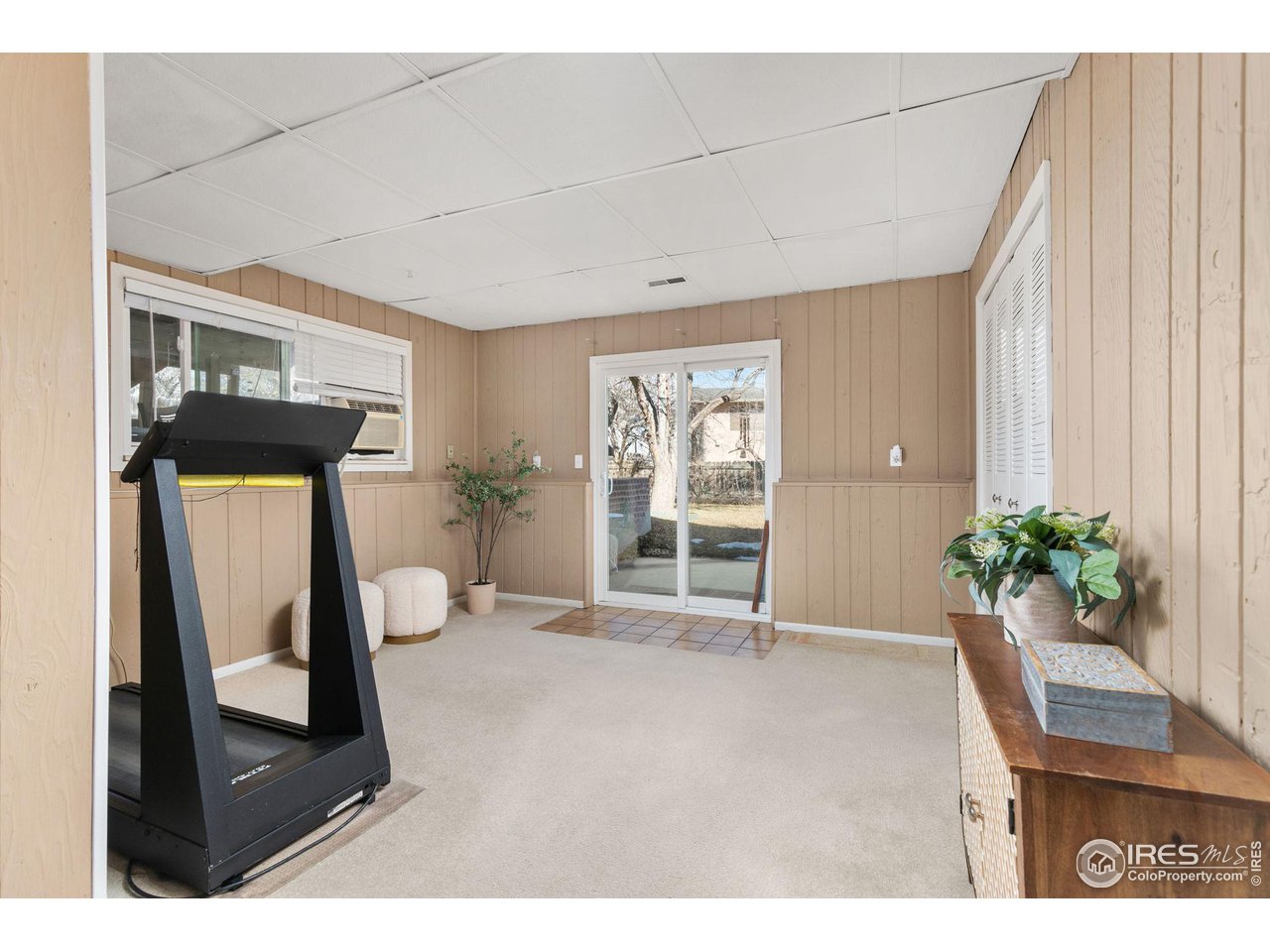 Exercise room with a treadmill and sliding glass door opening to the yard.
