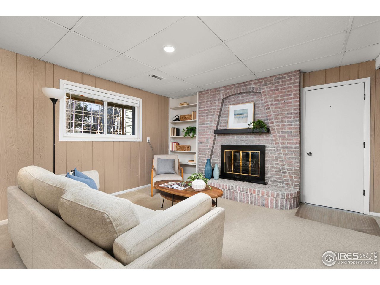 Living room with a brick fireplace, built-in shelves, and tan paneled walls.