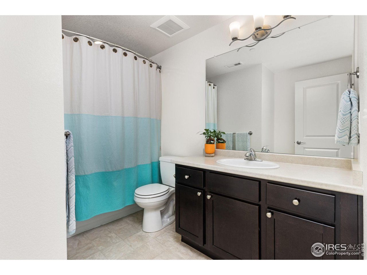 Bathroom with a dark wood vanity and turquoise-and-white shower curtain.