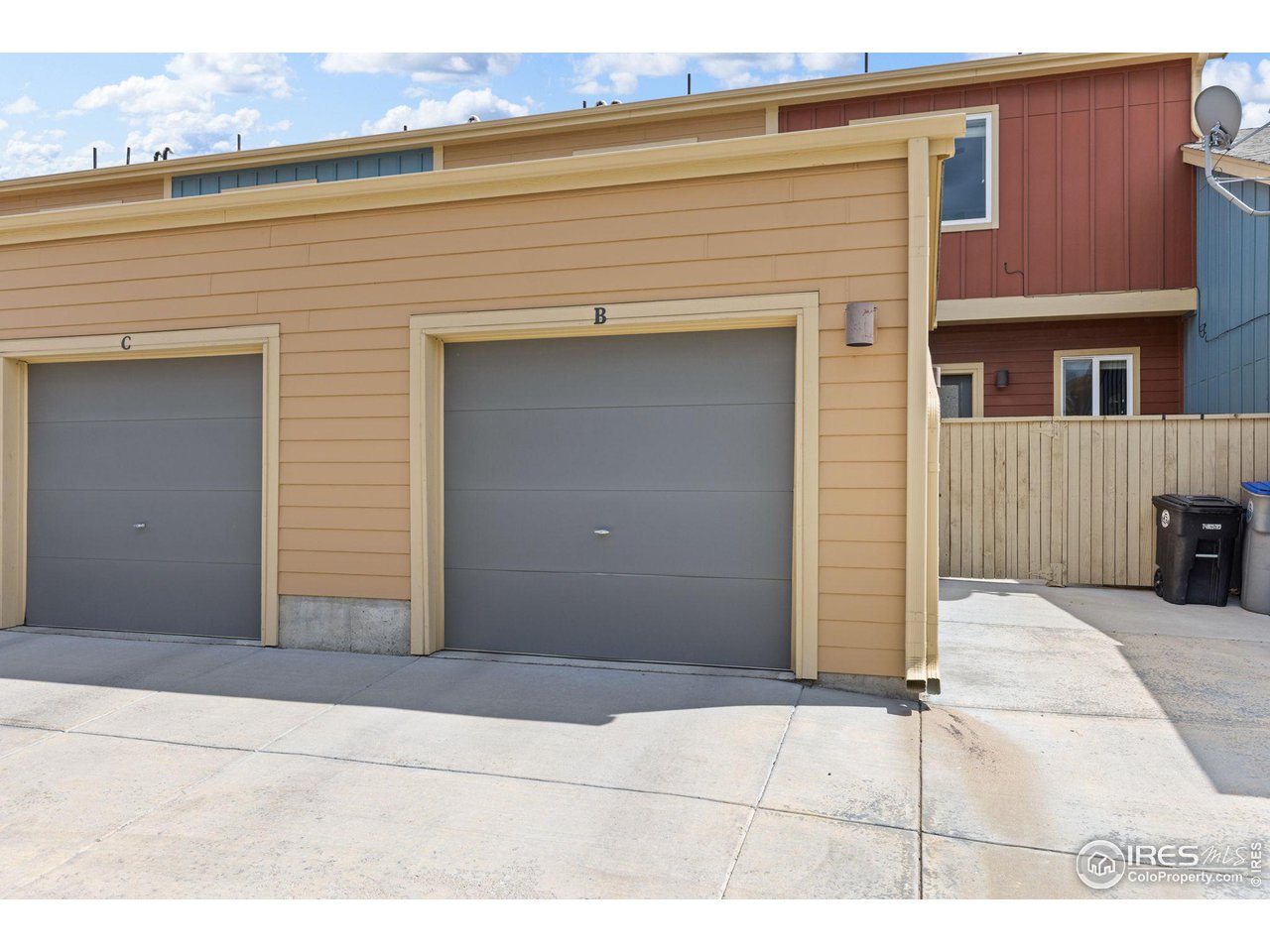 Tan-sided garage B with a gray door, beside garage C and a concrete driveway.
