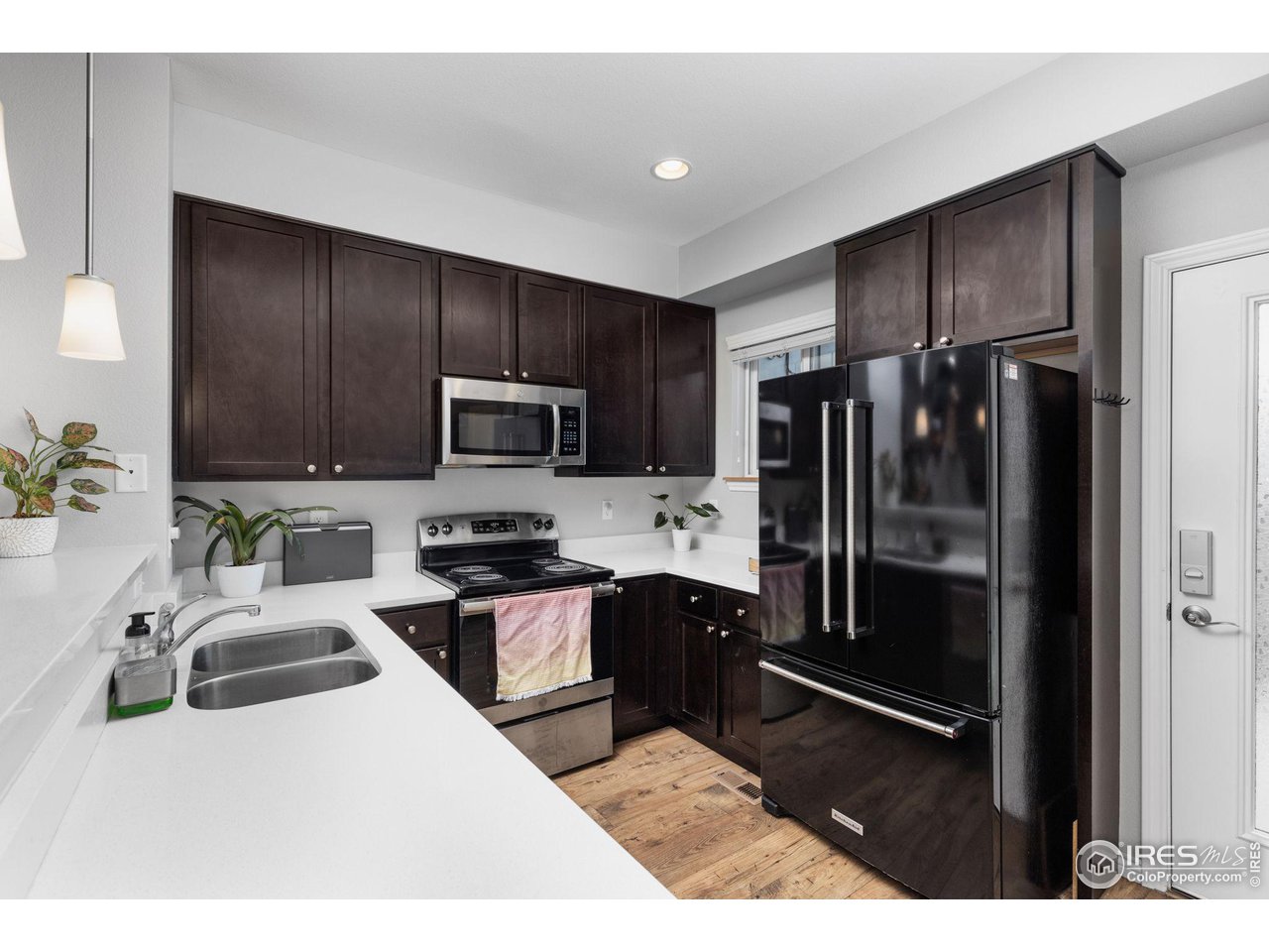 Kitchen with dark cabinets, white countertops, and a black French-door refrigerator.