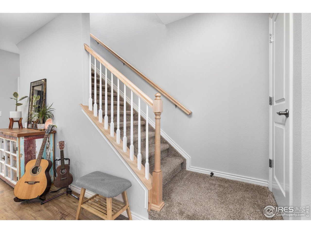 Entryway with carpeted stairs, light wood railings, two guitars, and a rustic console table.