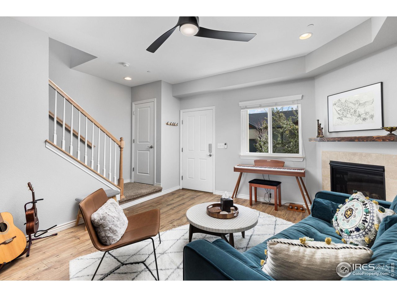 Furnished living room with a staircase, teal sofa, keyboard, and fireplace.