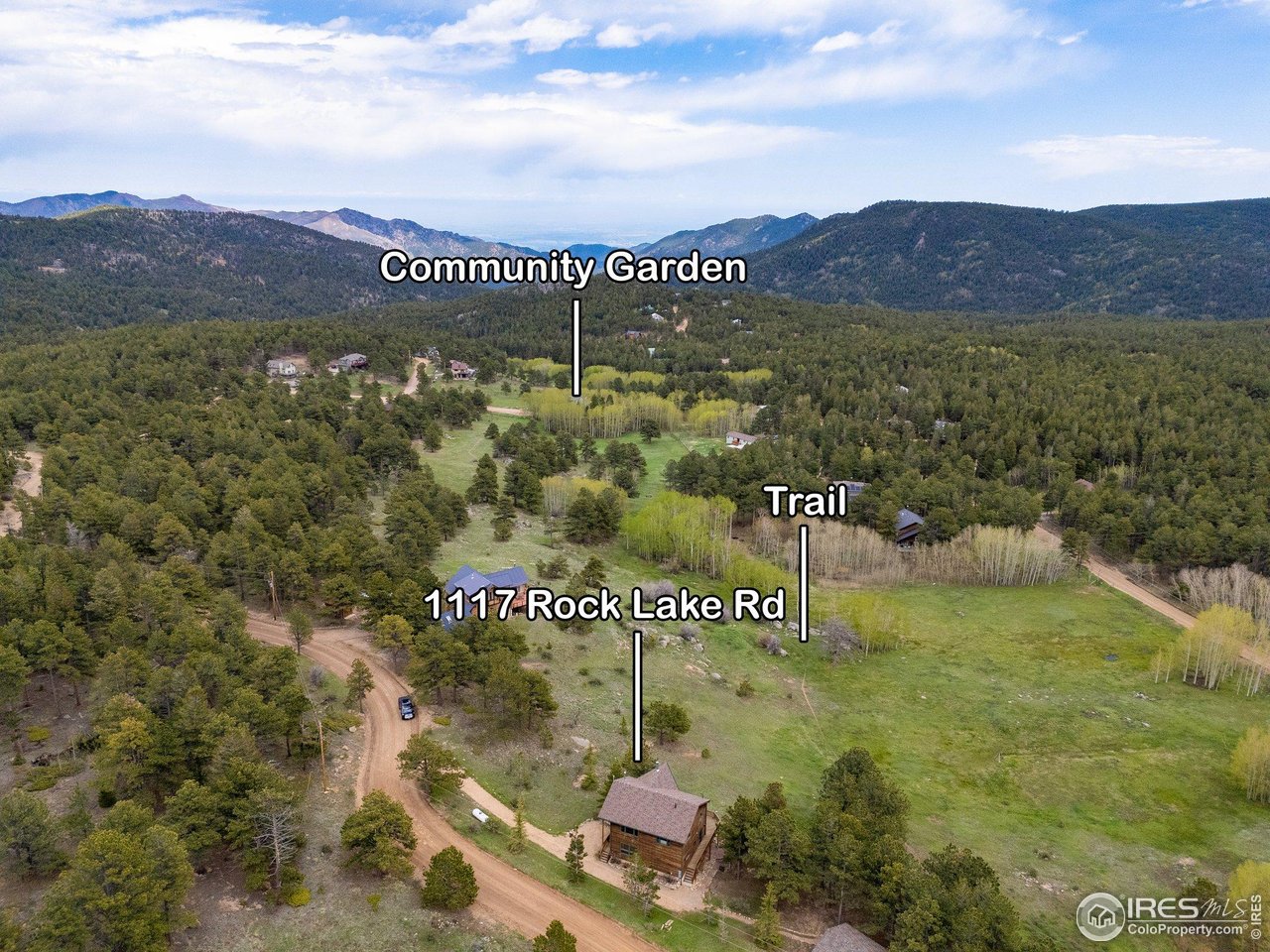 Aerial view of 1117 Rock Lake Rd in a forested mountain valley, with nearby trail and community garden labels.