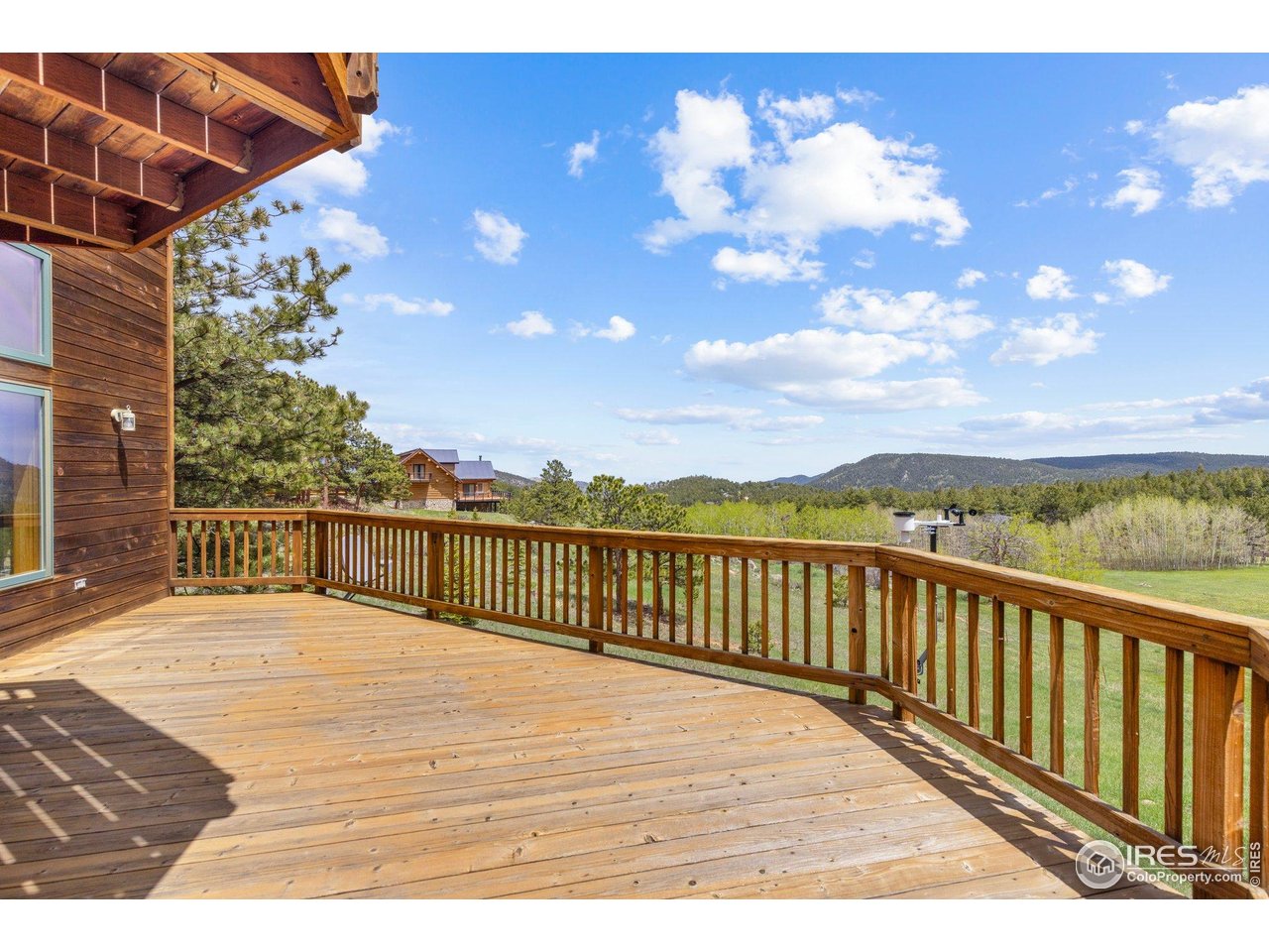 Wooden deck overlooking green trees and distant mountain ridges.