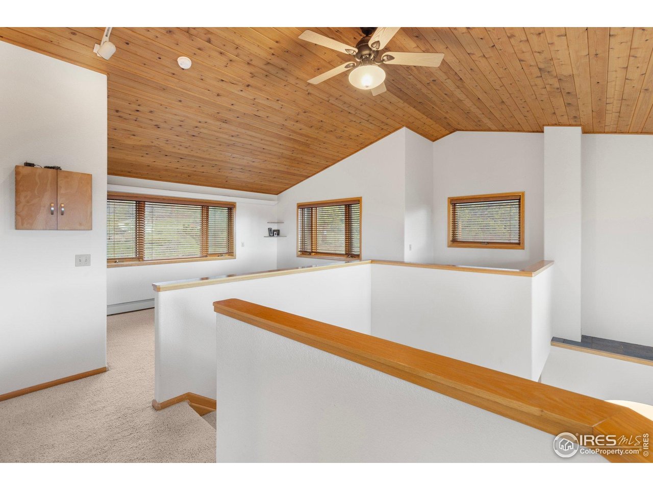 Interior landing with a vaulted wood ceiling, ceiling fan, and several windows.