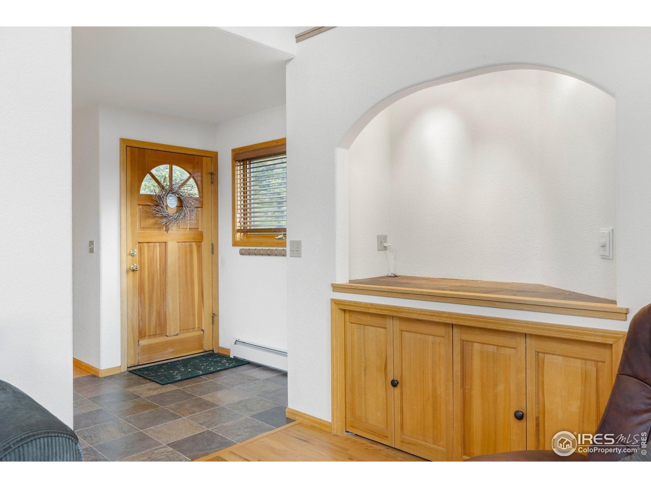 Entry foyer with a wood front door and built-in cabinetry beneath an arched alcove.