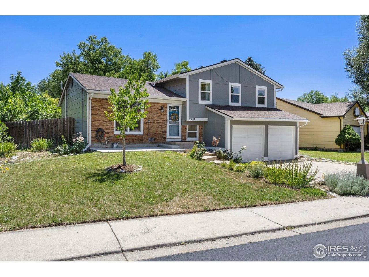 Gray and brick two-story house with a double garage and landscaped front lawn.