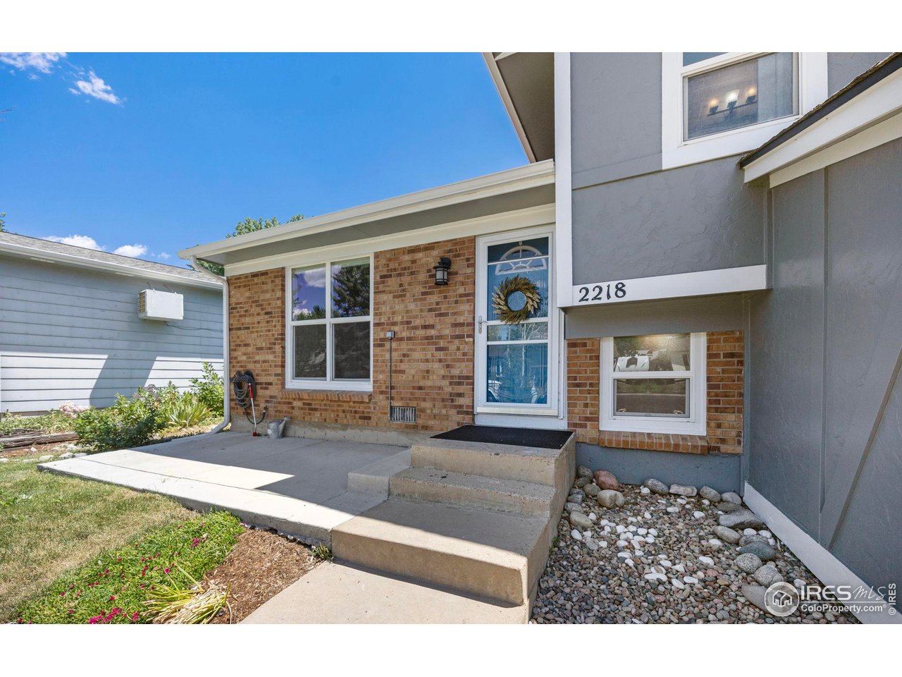 Home entrance with brick facade, gray siding, glass front door, and concrete steps.