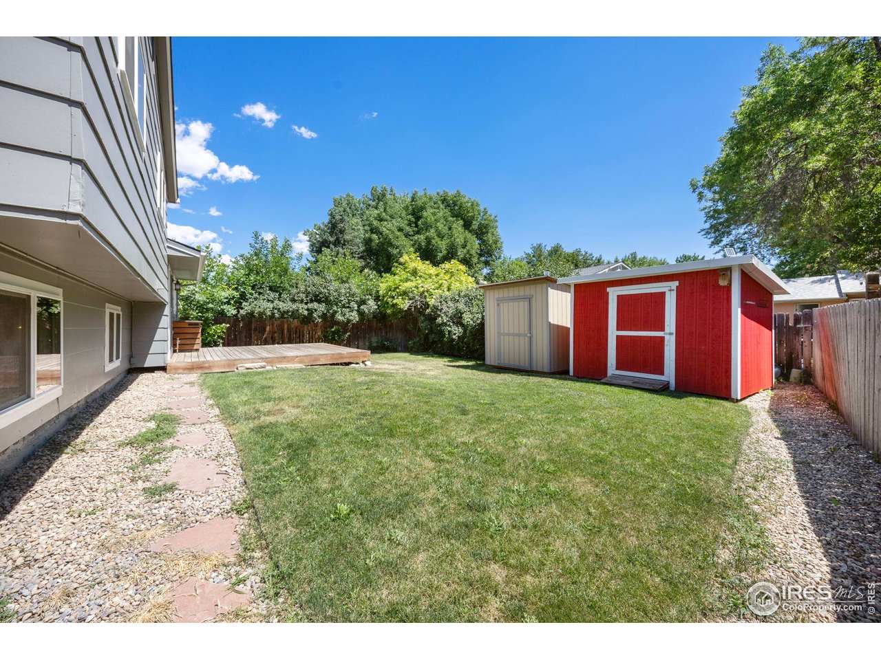 Backyard lawn with a raised deck and red-and-white storage shed.