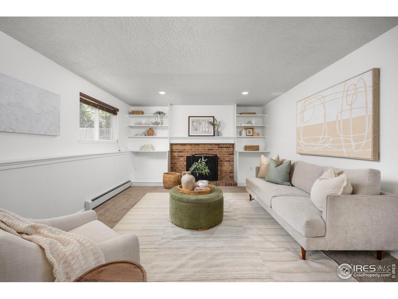 Staged living room with a brick fireplace, built-in shelves, and neutral sofas.