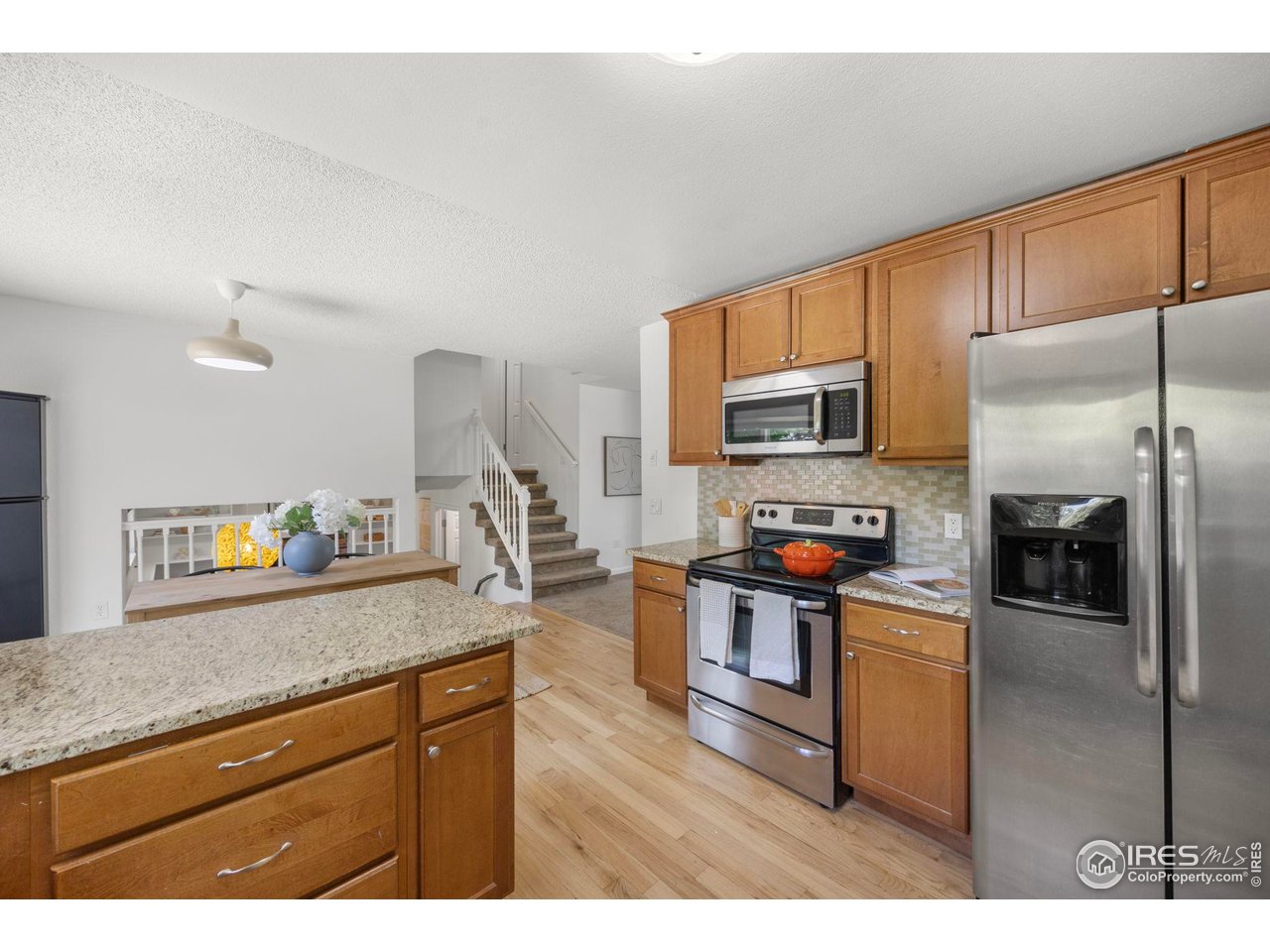 Kitchen with warm wood cabinets, granite island countertops, and stainless steel appliances.
