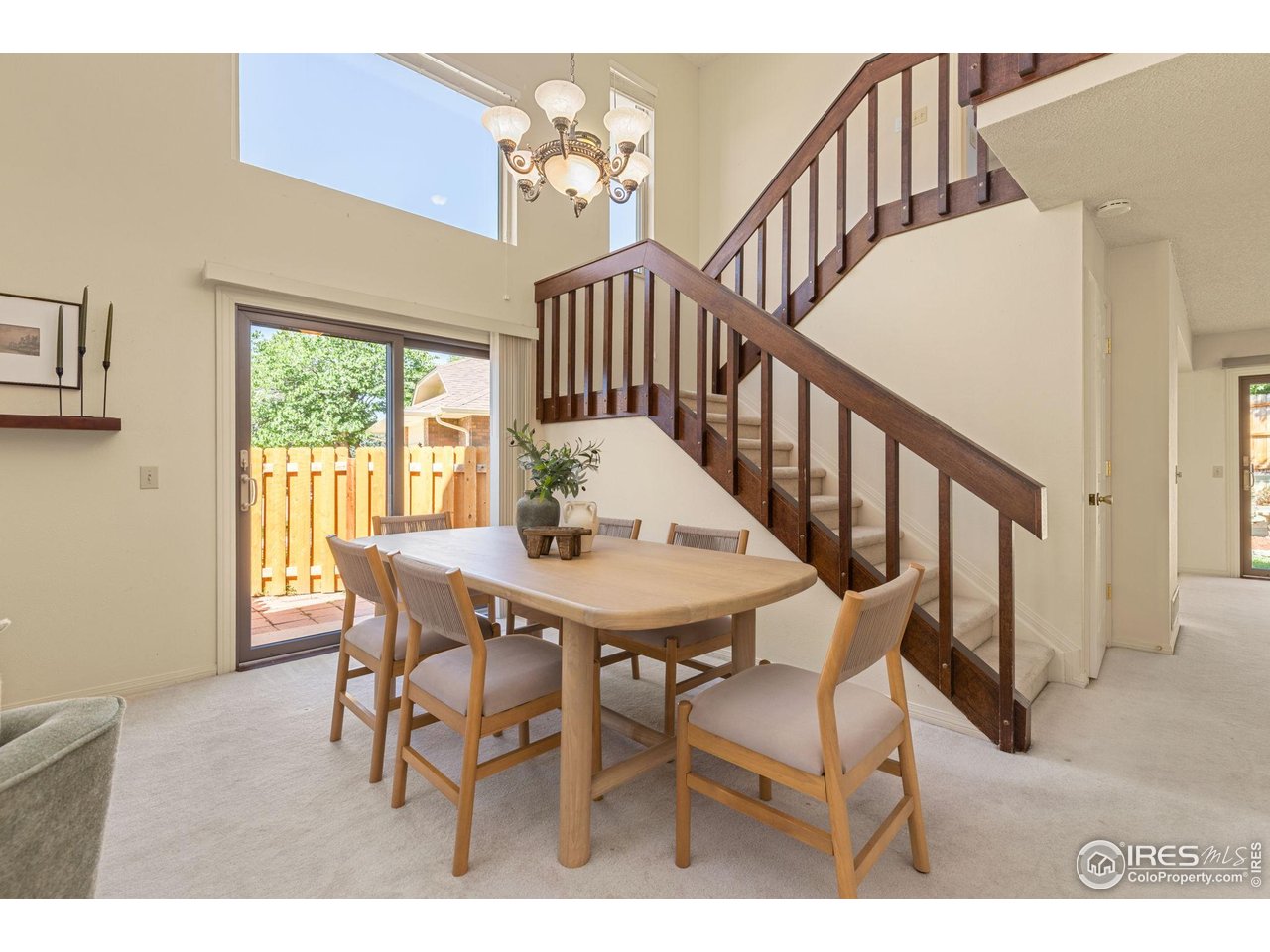 Dining area with a wood table beneath a dark staircase and a sliding door to the patio.