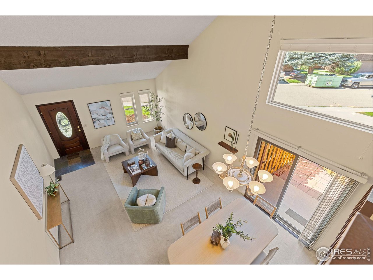 Living room with vaulted ceiling, exposed wood beam, chandelier, and sliding doors to a patio.