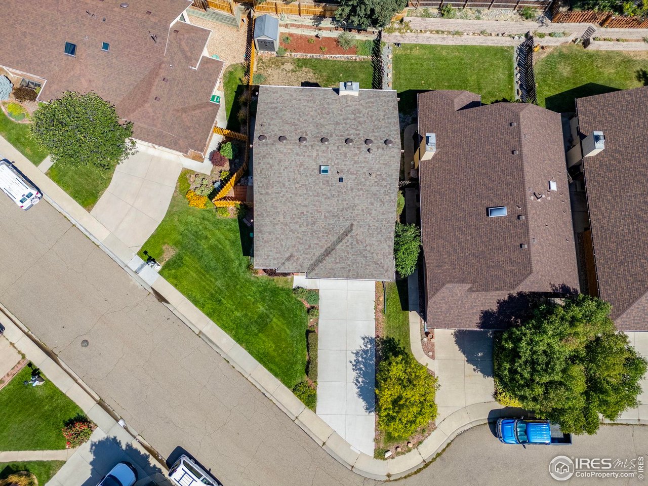 Aerial view of a home with a gray roof, lawn, driveway, and surrounding homes.