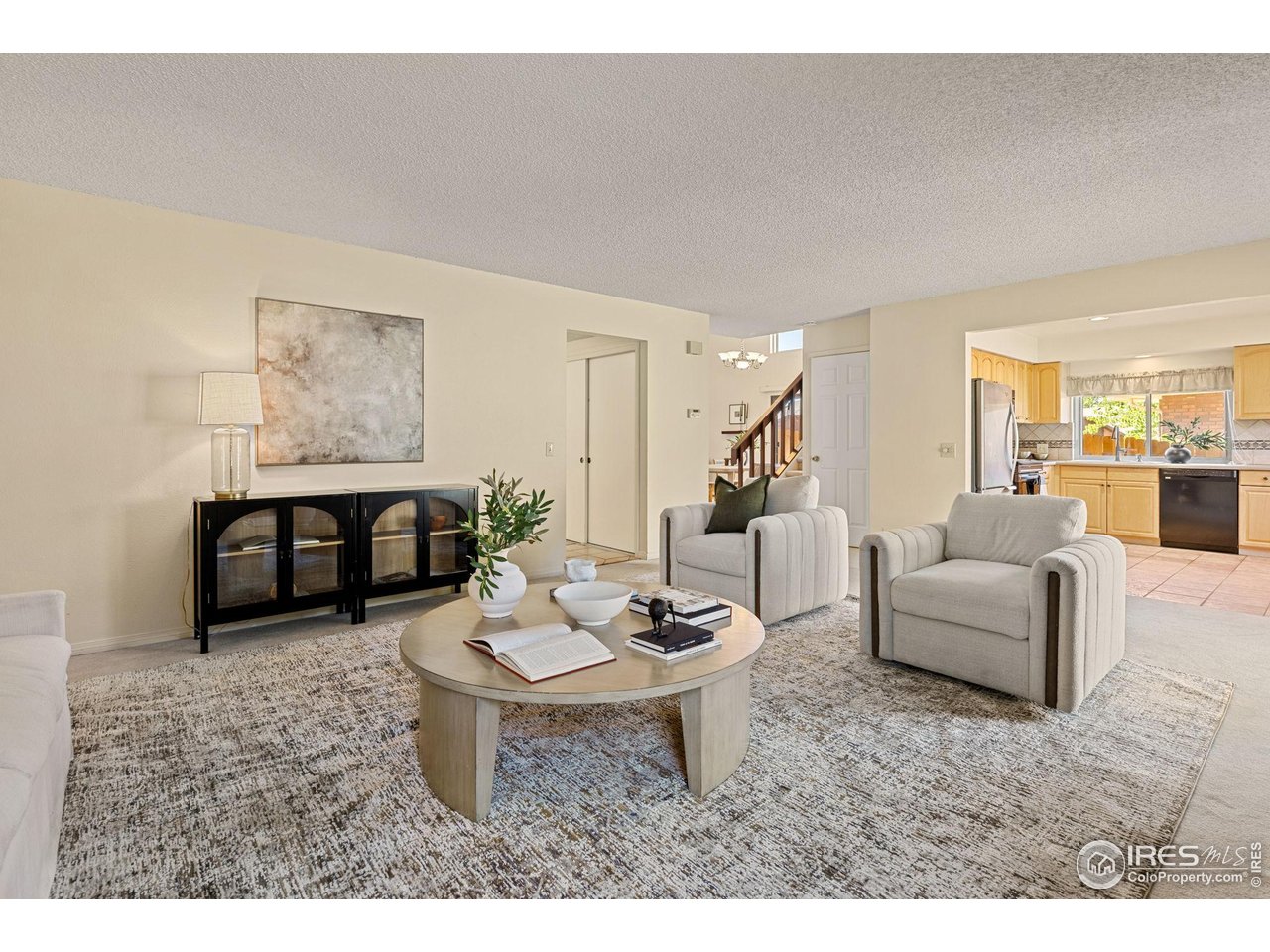 Living room with two armchairs, a round coffee table, and an open view into the kitchen.