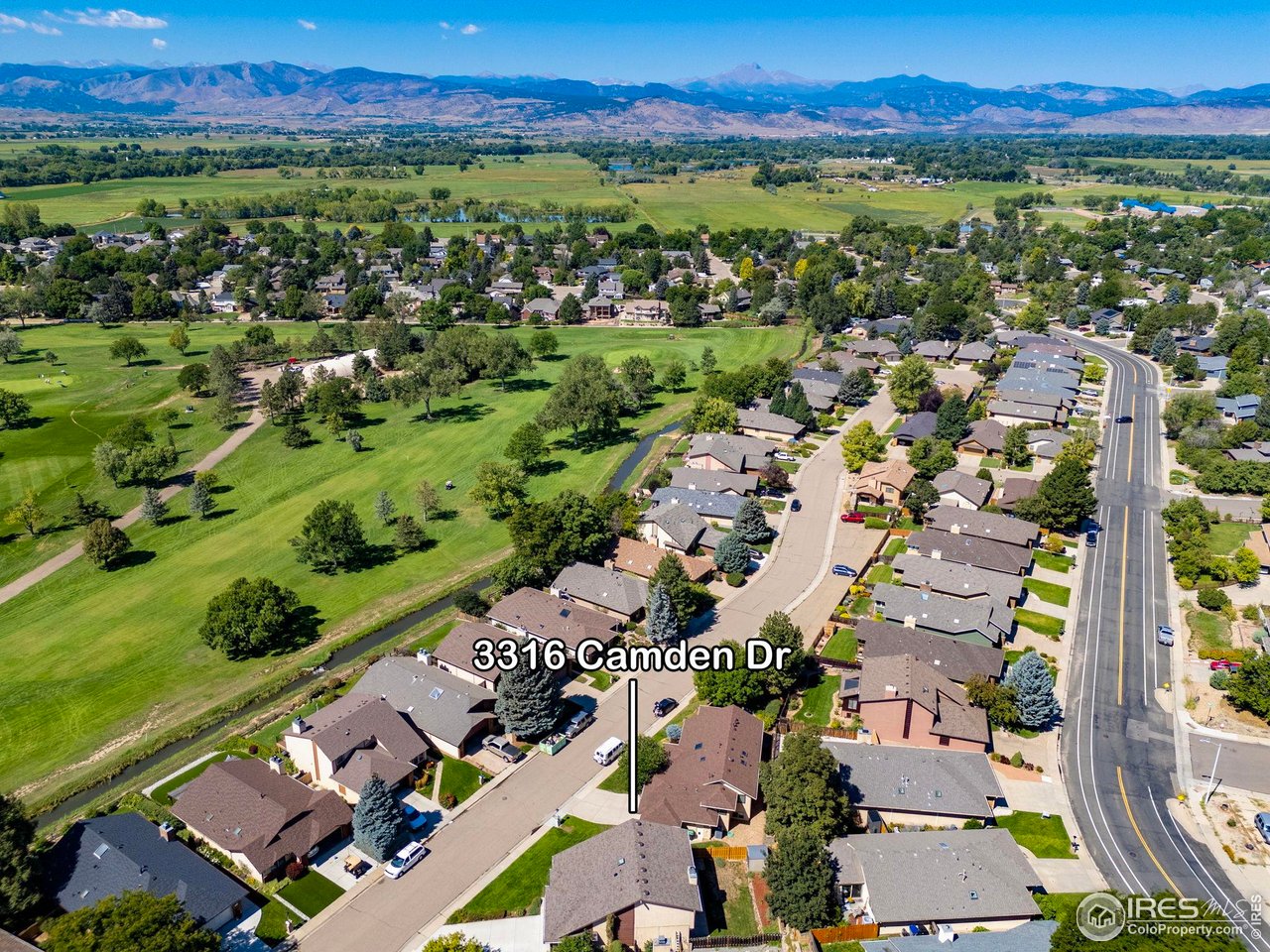 Aerial view of 3316 Camden Dr beside a greenbelt, with the Rocky Mountains in the distance.