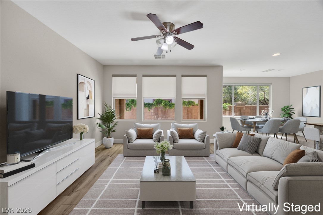 Virtually staged living room with light sofas, a ceiling fan, and an adjoining dining area.