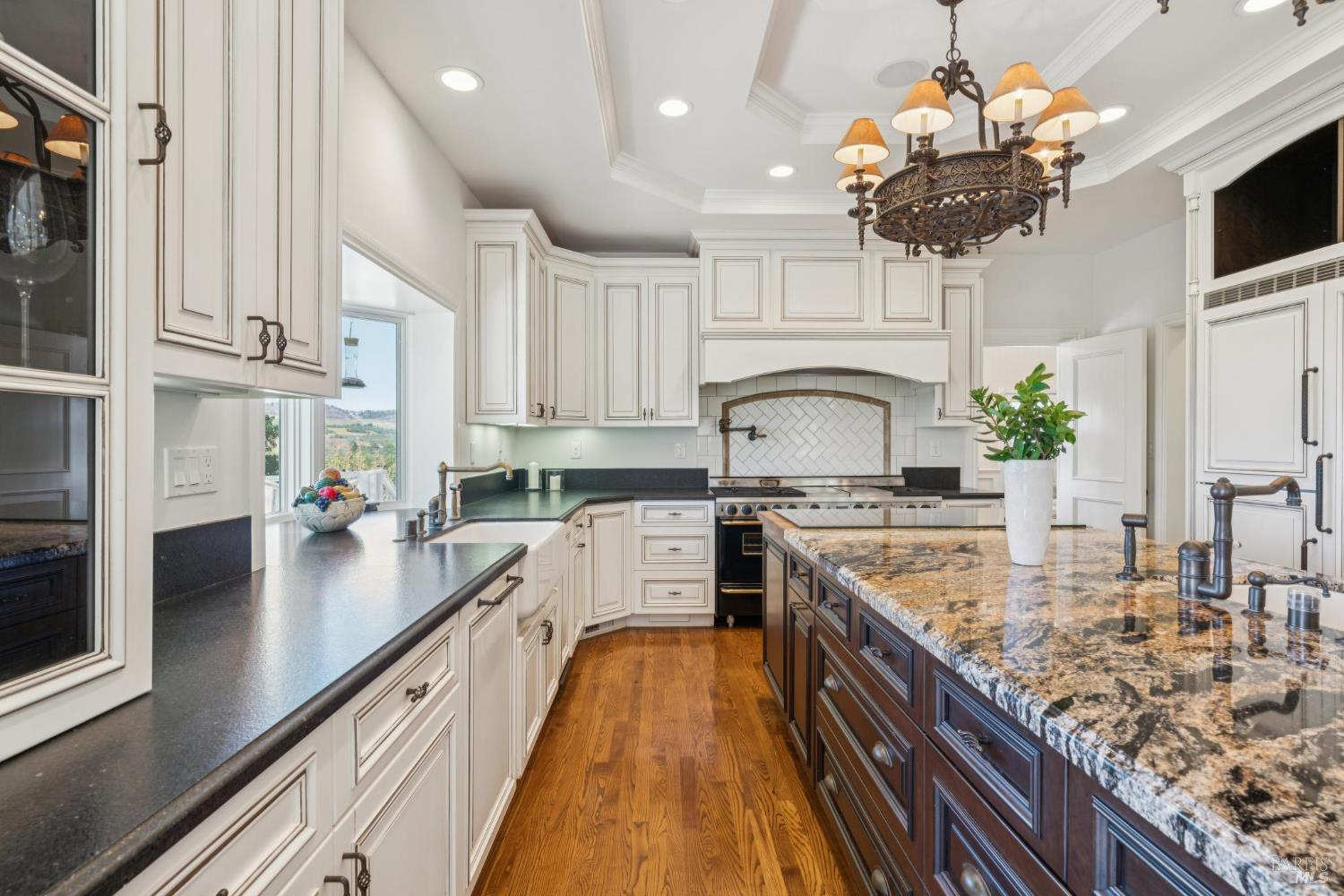 Bright kitchen with a granite island, white cabinetry, and hardwood floors.