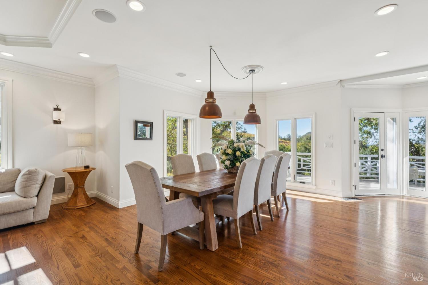 Dining room with a wooden table, upholstered chairs, hardwood floors, and glass doors to a deck.