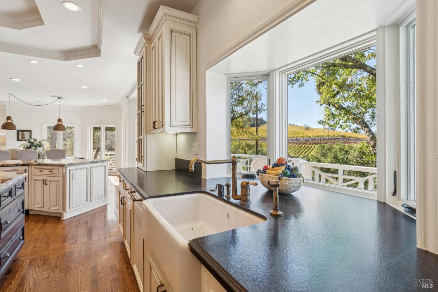 Kitchen with a large farmhouse sink and panoramic window overlooking vineyard rows.