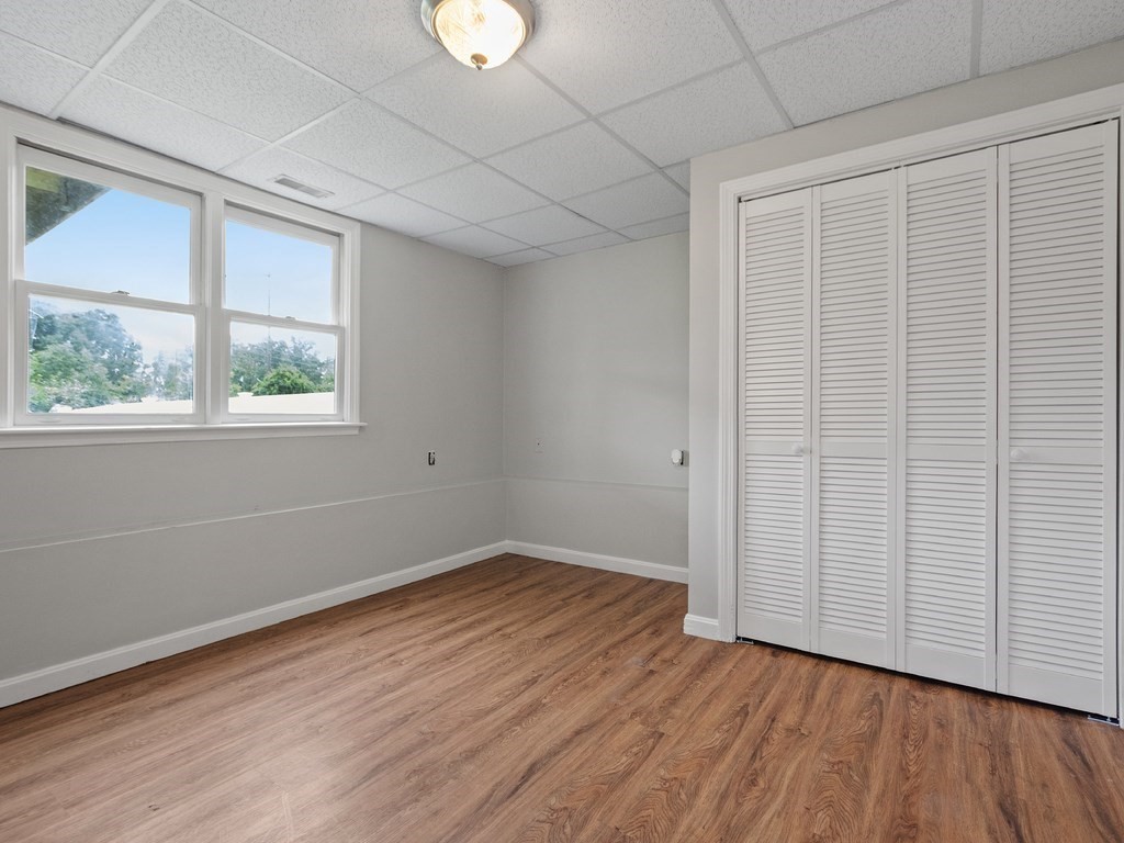 Empty room with wood-look flooring, two windows, and white louvered closet doors.