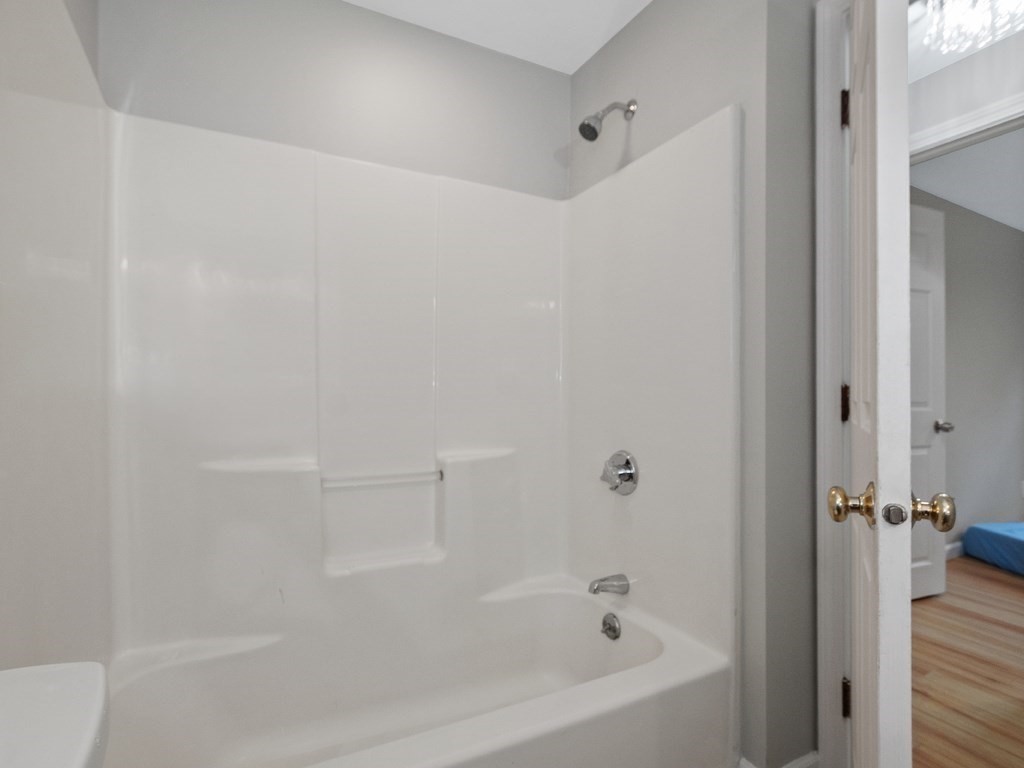 Bathroom tub and shower with built-in shelves and chrome fixtures.